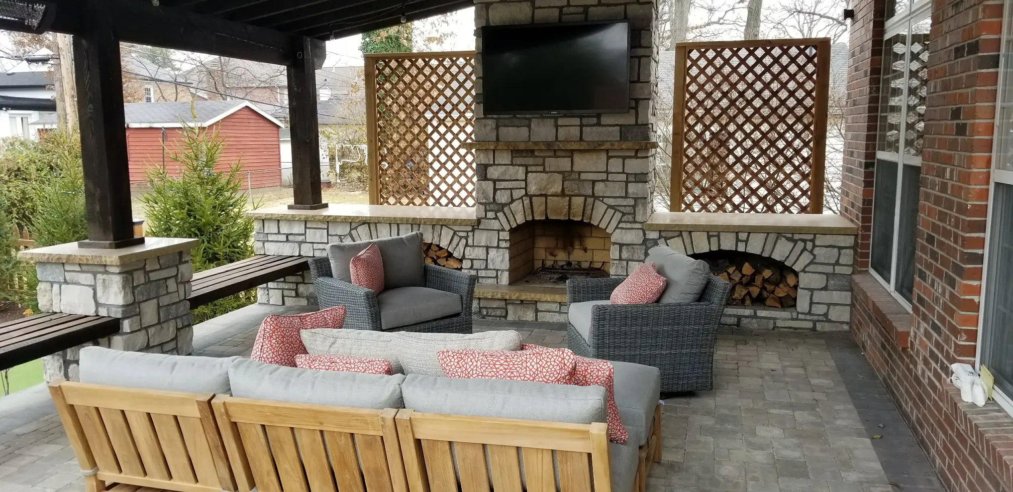 Covered wood pergola over paver patio with masonry outdoor fireplace, mounted TV, lattice screens and seating, Brentwood, Missouri